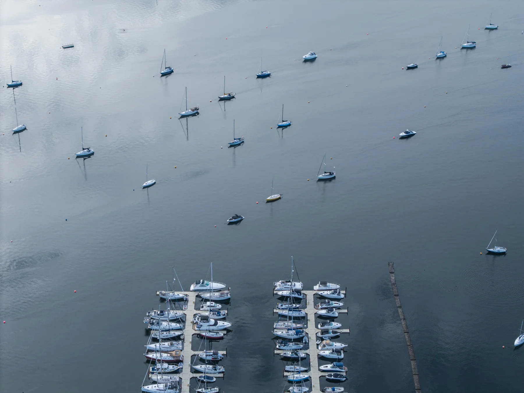 Aerial view of marina docks and sailboats on moorings