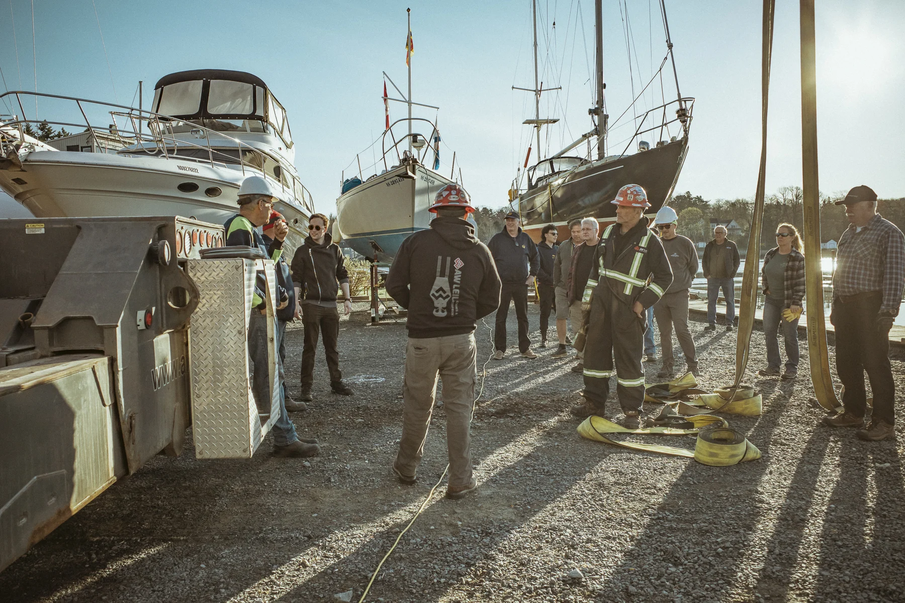 Club members and yard crew standing together among boats in the boatyard