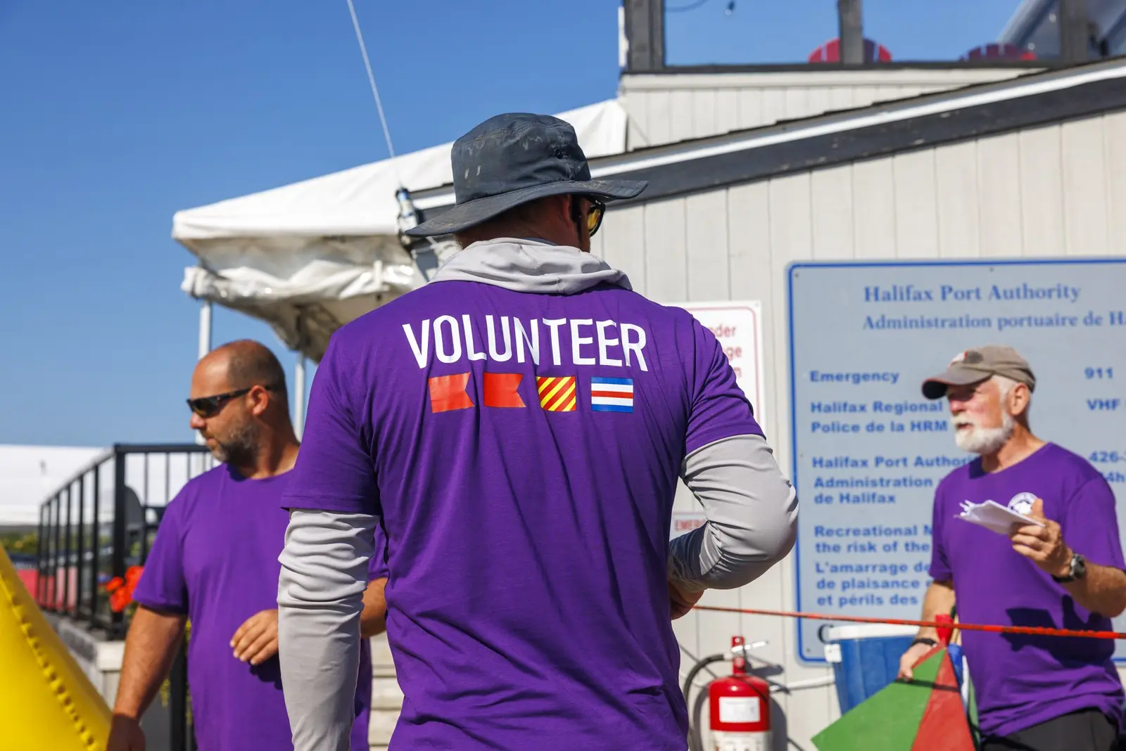 Three volunteers in purple shirts coordinating at the waterfront